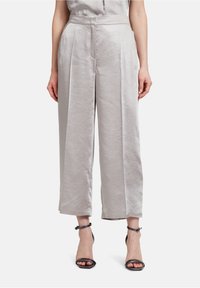 Ljusgrå, vida byxor i mjukt tyg, med hög midja och plissering fram. Matchas med svarta klackskor med band.