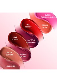 Colorful lip products displayed in smooth curves, featuring shades: Red Velvet, Love Potion, Hopeful Romantic, Milk & Cookies, Bed of Roses, Peach Blur, and Super Candy Clouds.