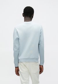 Φωτεινό γαλάζιο φούτερ με μακρυά μανίκια, ριμπ μανσέτες και στρογγυλή λαιμόκοψη. Μαλακό, υφασμάτινο υλικό με λεπτές λεπτομέρειες στο πίσω μέρος.