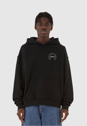 Svart hettegenser med frontlomme. Har et brodert grafisk motiv på brystet. Laget av myk stoff, avslappet passform og lange ermer.