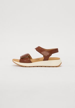 Brun læder sandal med to justerbare remme, polstret fodseng og tyk hvid struktureret sål vist fra siden.
