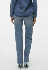 Lyseblå denimjeans med rett snitt, to baklommer og subtil falming. Kombinert med lyseblå høye sko.