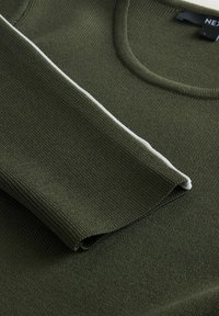 Olijfgroen gebreide trui met een geribbelde textuur, voorzien van een ronde halslijn en een witte accentstreep langs de rand van de mouw.