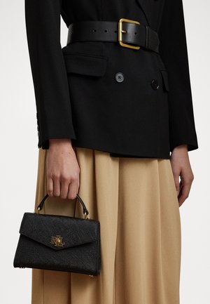 Black structured handbag with a textured finish, gold hardware, and a top handle. Worn with a black blazer and beige skirt.