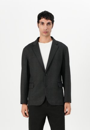 Gray textured blazer with a notch lapel, single button closure, and two front pockets, worn over a white shirt. Tailored fit.