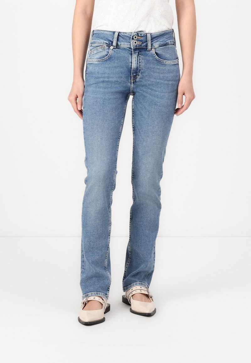 Ljust blå denimjeans med slim fit, fem fickor, en flerknäppning och subtila urtvättade detaljer. Pages med beige ballerinaskor.