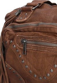 Bruine leren rugzak met metalen studs en ritsen. Gelaagde oppervlakte met een slouchy ontwerp. Inclusief zij- en voorvak met rits.