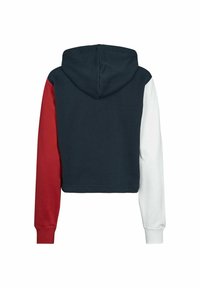 Sweat à capuche avec corps bleu marine, manche gauche rouge, manche droite blanche et capuche, vu de dos sur fond blanc.