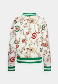 Biała kurtka bombarderka z zielonymi paskami u mankietów i kołnierzu, ozdobiona kolorowymi wzorami z marynistycznymi kotwicami, linami i różą kompasową.