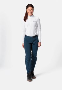 Wit shirt met lange mouwen en een halve ritssluiting bij de kraag, gecombineerd met nauwsluitende, donker petrolgroene broek en zwarte schoenen. Slim-fit ontwerp met een gladde textuur.
