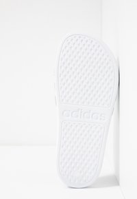 Fehér gumi szandál talp, textúrált tapadási mintával. Az "adidas" logó dombornyomott formában szerepel. Lapos kialakítás, lekerekített szélekkel és enyhe emelkedéssel.