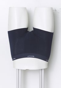 Κάτω μέρος του κορμού κούκλας που φοράει μαύρα μποξερ GANT μπροστά σε λευκό φόντο.