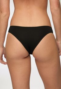 Slip bikini in cotone nero, design a vita bassa con fianchi stretti, texture liscia, dettagli di cucitura semplici e uno stile minimalista.