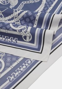 Écharpe en soie avec un motif de chaînes bleu et blanc, portant la marque "GUESS," mise en valeur par des bordures contrastées et des détails complexes.