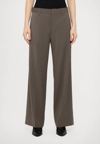 Γκρι παντελόνι σε φαρδιά γραμμή, κατασκευασμένο από λείο, υφασμάτινο υλικό, με κλασική μέση και βρόχους ζώνης, φορεμένο με μυτερές μαύρες γόβες.
