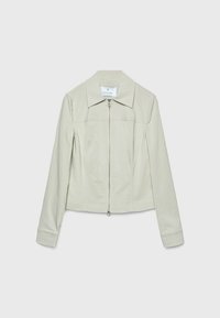 Lysebeige kvinders jakke med lange ærmer, krave og lynlåslukning foran mod en ensfarvet hvid baggrund.