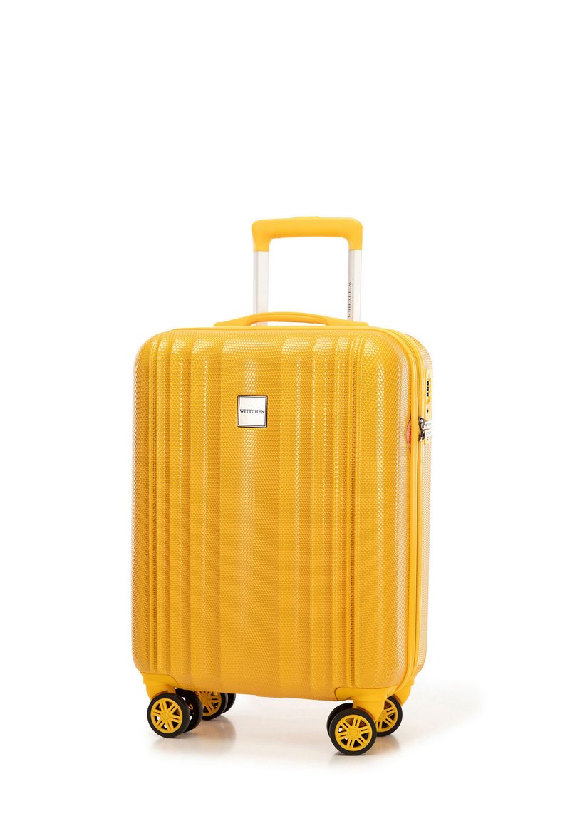 Geel harde koffer met een gestructureerd oppervlak, geribbelde ontwerpelementen, multidirectionele zwarte wielen en een uitschuifbare handgreep.