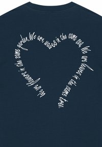 Tamsiai mėlynas medvilninis marškinėlis, turintis baltą širdies formos teksto dizainą, su citata rašyta kursyvu.