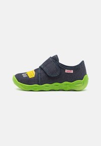 Denim slip-on sko med grønn gummisåle, borrelås og trykt design med et gult aksent. Teksturert overdel med kontrasterende sømmer.