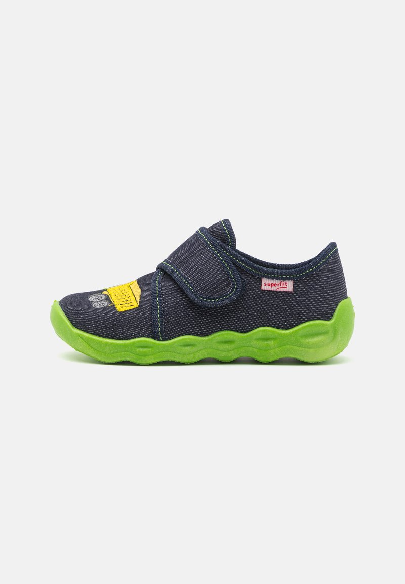 Denim slip-on sko med grønn gummisåle, borrelås og trykt design med et gult aksent. Teksturert overdel med kontrasterende sømmer.