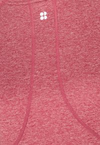 Punainen heather-kuvioinen urheilupaita, jossa on näkyvät ompeluviivat ja pieni valkoinen logo. Pehmeä rakenne, istuva muotoilu.