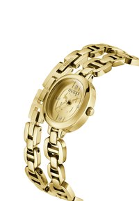 Orologio da polso in metallo dorato con cassa ovale, bracciale a maglie, indicatori in diamante e un quadrante dorato abbinato con il marchio "Guess."