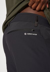 Μαύροι παντελόνια DuraStretch με λεία υφή, εφαρμοστό σχέδιο και διακριτό πουά μοτίβο στη μέση με τσεπάκι με φερμουάρ.