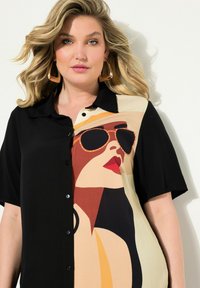 Camicia con una sezione nera e un design grafico crema, arancione e bordeaux di una donna con occhiali da sole; maniche corte, stile con bottoni.