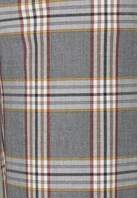 Grå och vit rutigt tyg med röda, svarta och gula ränder. Mönstret har linjer med varierande bred och en texturerad väv.