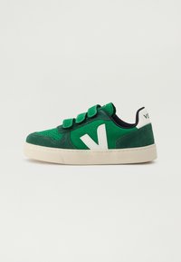 Zelené semišové tenisky se suchými zipy. Jsou doplněny bílým logem na boku a texturovanou krémovou gumovou podrážkou. Kontrastní námořnická podšívka a akcenty.