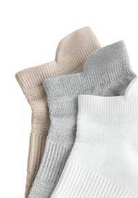 Tre par strumpor i beige, grå och vit. De har en ribbad textur och olika stickade mönster på mudden.