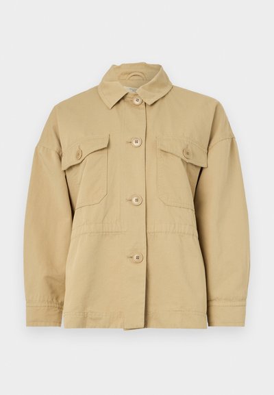 Beżowa bawełniana kurtka z kołnierzem, zapięciem na guziki z przodu oraz dwiema kieszeniami na piersiach. Posiada luźny krój i gładką fakturę.