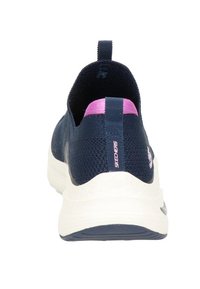 Marinblå slip-on sneakers med en texturerad stickad ovandel, rosa detaljer på hälen, och en tjock vit mellansula, med en logotyp på sidan.