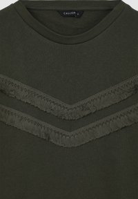 Felpa verde scuro con due design a chevron frangiati realizzati in tessuto coordinato. Presenta un colletto a coste e un materiale morbido e strutturato.