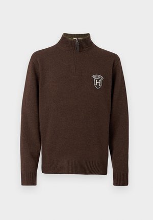 Brauner Strickpullover mit hohem Kragen, halbem Reißverschluss, gerippten Bündchen und Saum. Mit einem Logo-Patch auf der Brust.