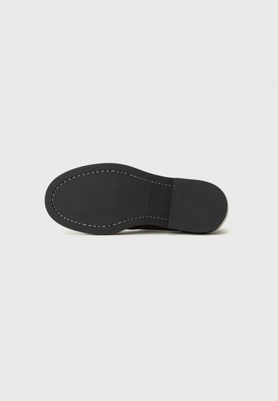 Zwarte schoenzool met een gladde afwerking, voorzien van witte stiksels langs de rand en een plat ontwerp voor stabiliteit.