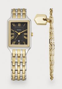 Montre en métal argenté et doré avec un cadran noir rectangulaire, chiffres romains, sous-cadran et un bracelet à maillons assorti. Accents dorés sur les éléments métalliques.