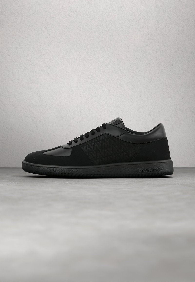 Baskets basses noires avec lacets noirs, panneau latéral texturé, bout lisse et semelle embossée du logo Valentino.