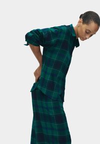 Grøn og marineblå ternet skjorte med afslappet pasform, knaplukning foran, lange ærmer og buet kant, parret med matchende ternede bukser.