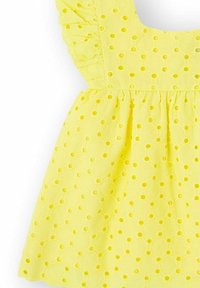 Vestido amarillo con una tela texturizada que presenta recortes circulares. Detalle de escote con volantes y cintura fruncida para un toque adicional de estilo.