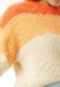 Suéter de punto difuso con rayas horizontales en naranja, amarillo y crema, con un cuello redondo y corte relajado. Textura suave y ligero.