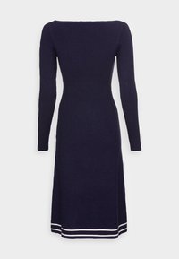 Marineblaues Langarmkleid mit weitem Ausschnitt, tailliertem Oberteil und drei weißen Streifen am Saum. Glatte Stricktextur.