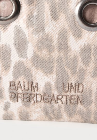 Ύφασμα με μοτίβο ζώου σε μπεζ και καφέ χρώμα, διακοσμημένο με κεντημένο γερμανικό κείμενο "BAUM UND PFERDGARTEN" και δύο μεταλλικά κόσκινα.