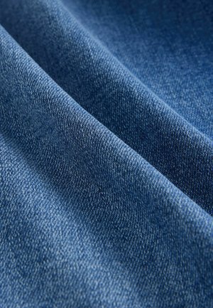 Denimstoff in tiefblau mit glatter Textur. Das Material zeigt ein dezentes Webmuster, das seine Haltbarkeit und weichen Griff unterstreicht.