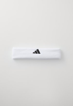 Bela bombažna športna trak za glavo z črnim logotipom s tremi črtami na strani. Ozek, mehak material s gladko teksturo.