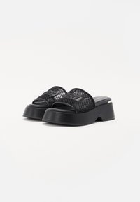 Black platform slides feature a mesh upper with an embossed logo, a contoured sole, and a smooth, textured surface.
