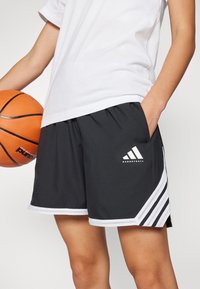 Melni basketbola šorti ar baltām akcentiem, ar elastīgu vidukli, sietiņa detaļām un Adidas logotipu priekšā.