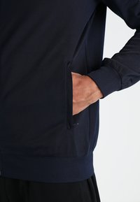 Mariene sweatshirt met een zijzak, ribgebreide manchetten en elastiek aan de onderzoom. Gladde stof met een subtiele textuurdetail.