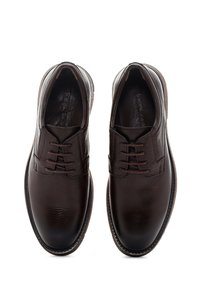 Une paire de chaussures élégantes en cuir brun foncé à lacets avec une finition texturée et des semelles en caoutchouc brun, vues de dessus sur fond blanc.