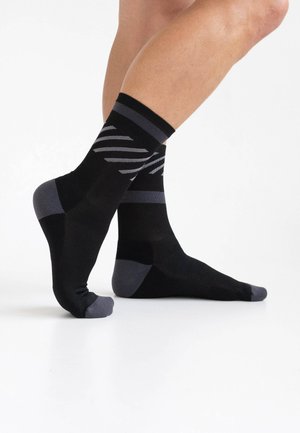 Schwarz-grau gestreifte Socken mit verstärkter Zehen- und Fersenpartie, aus dehnbarem Material mit glatter Textur.